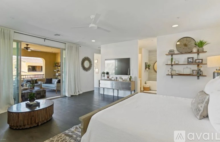 A modern bedroom with a large bed and a balcony with a view of the city.