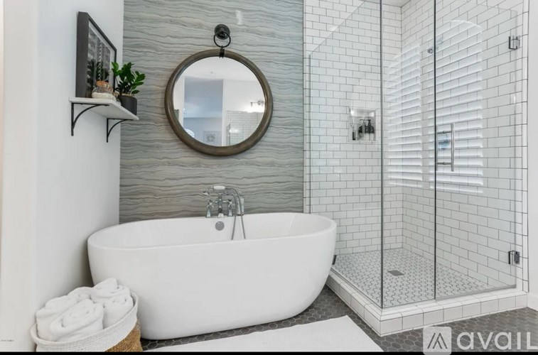 A modern bathroom with a freestanding bathtub and a round mirror above it.