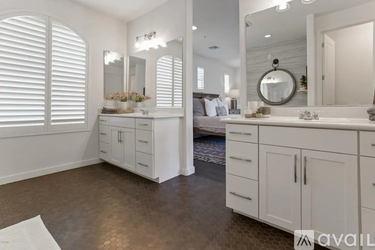 A bathroom with white cabinets and a large mirror.