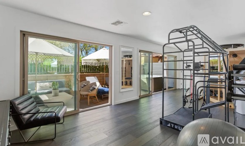 A modern home gym with a black leather chair and a TRUFitness treadmill.