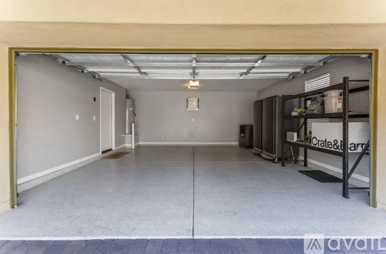 A spacious garage with a concrete floor and a Crate & Barrel shelf.