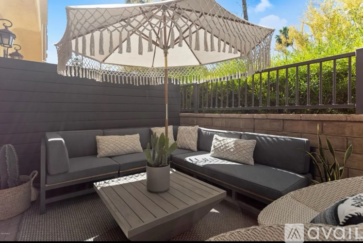 A patio with a grey sofa, a wooden table, and a white cactus.