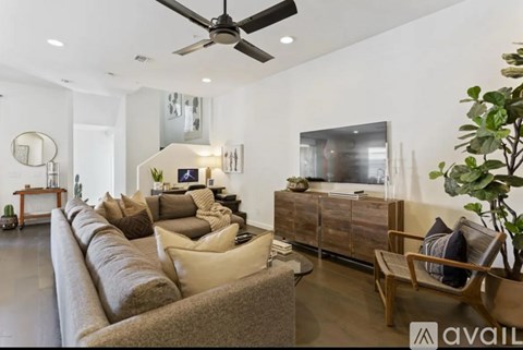 A living room with a long couch and a ceiling fan.