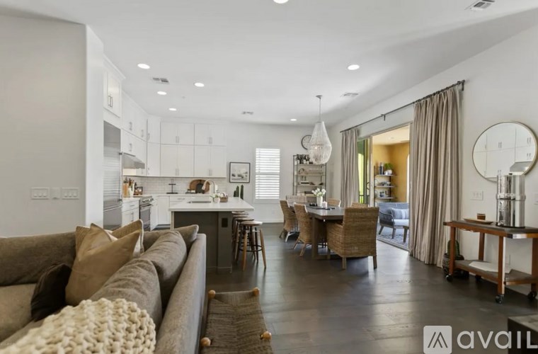 A modern living room with a brown sofa and a dining area in the background.