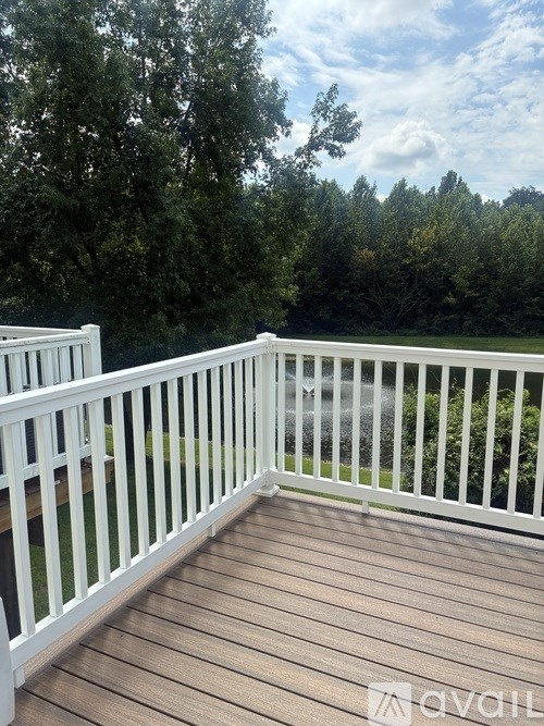 A deck with white railings overlooks a wooded area.