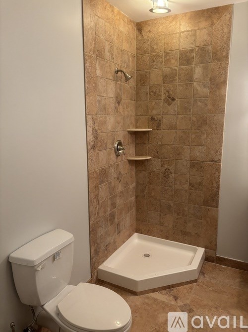 A bathroom with a toilet, a tub, and a tiled wall.