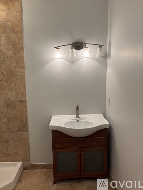 A bathroom with a sink, a tub, and a wall-mounted light fixture.