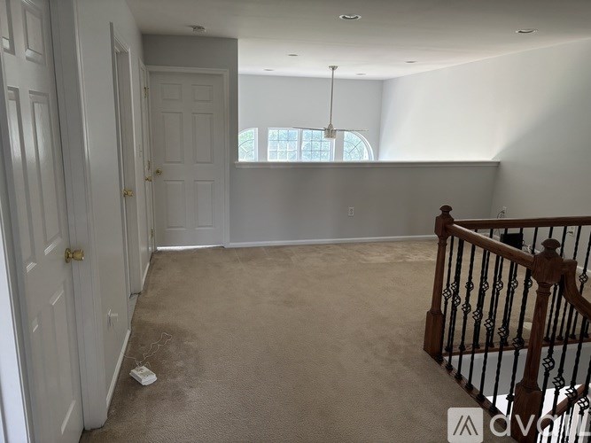A room with a carpeted floor, a wooden staircase, and a window.