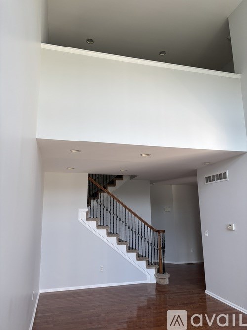 A staircase with a wooden handrail and a white wall.