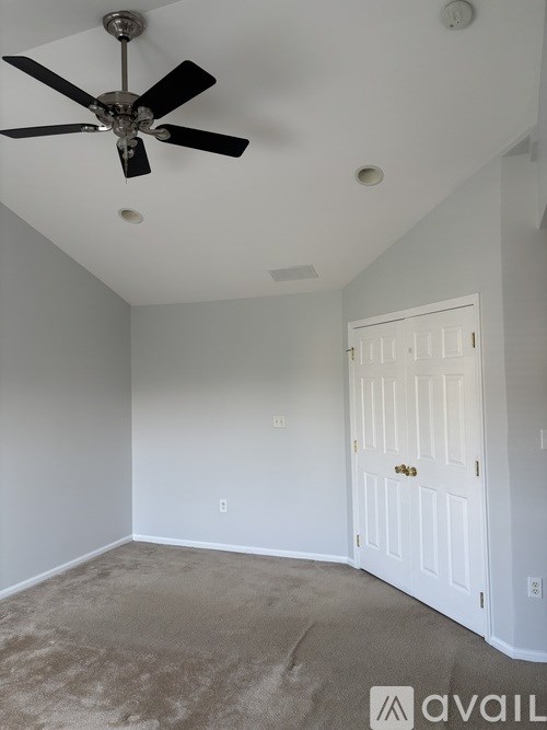 A room with a ceiling fan and a closed white door.