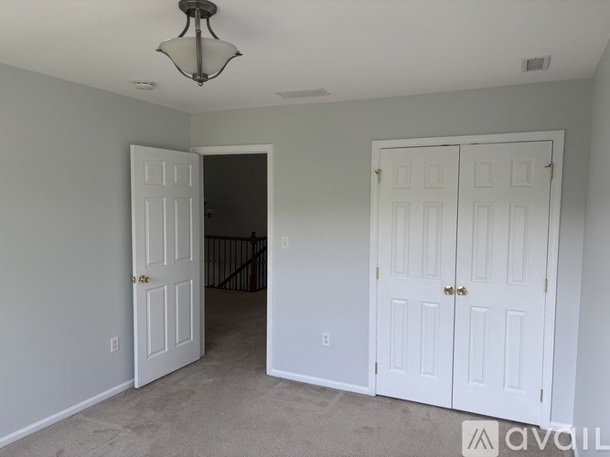 A room with two white doors and a chandelier hanging from the ceiling.