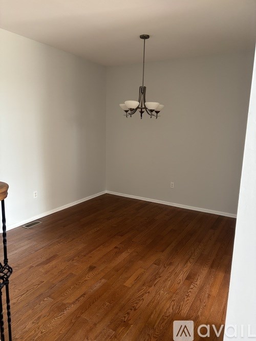 A room with wooden flooring and a chandelier hanging from the ceiling.