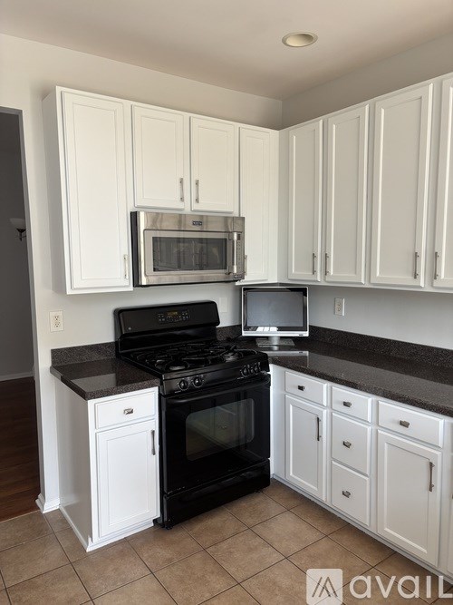 A kitchen with black appliances and white cabinets.
