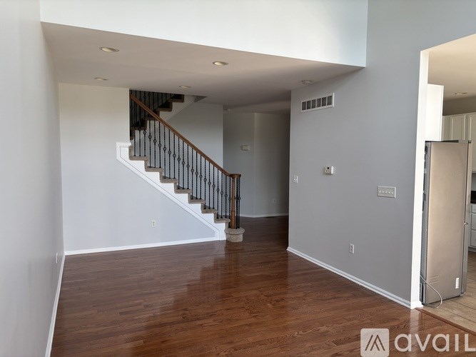 A spacious room with a staircase and wooden flooring.