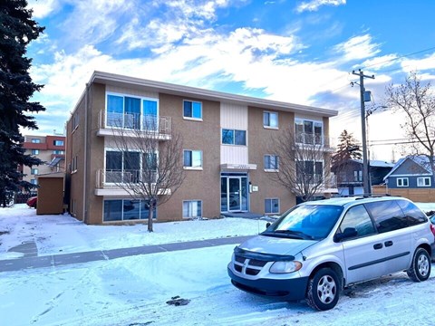 A silver Dodge van is parked in front of a two-story apartment building.
