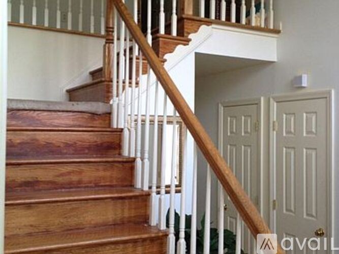 A wooden staircase with white railings leads to a landing with a white door.