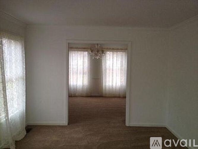 A room with a chandelier and a window with curtains.