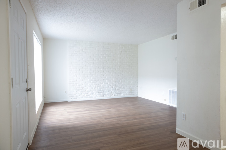 A room with wooden flooring and a white brick wall.