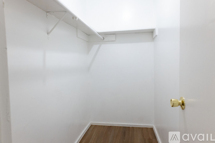A white room with a wooden floor and a gold door handle.