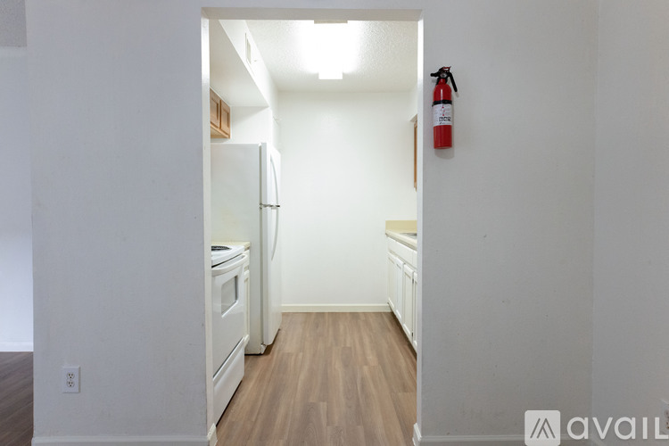 A kitchen with a white fridge and a red fire extinguisher on the wall.