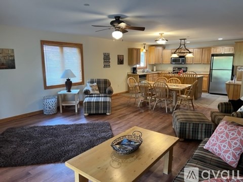 A living room with a ceiling fan and a dining table with chairs.
