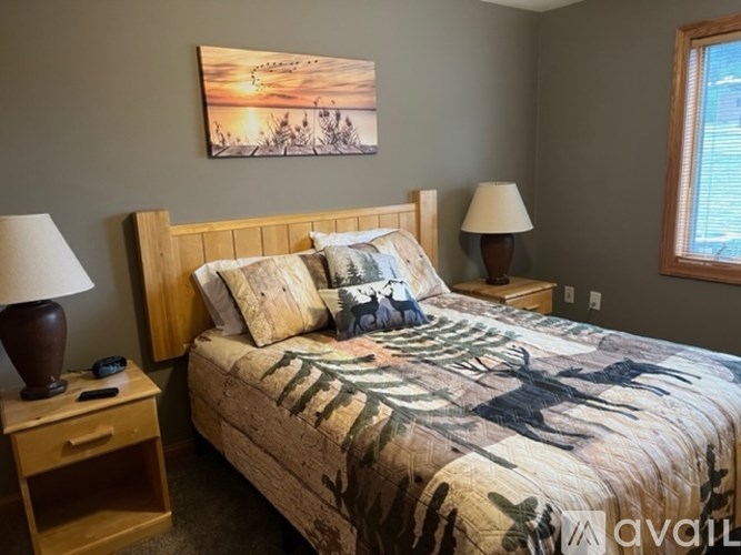 A bedroom with a bed, two lamps, and a painting on the wall.