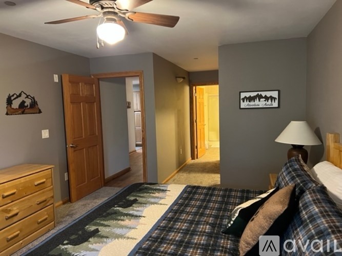 A bedroom with a bed, dresser, and ceiling fan.