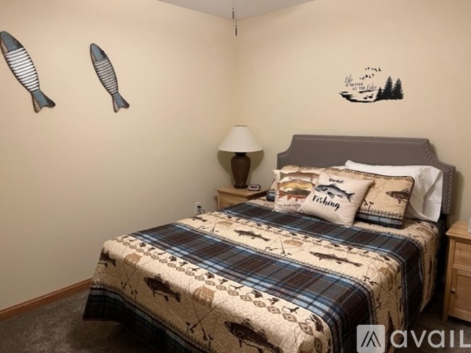 A bedroom with a bed, pillows, a lamp, and fish decorations on the wall.
