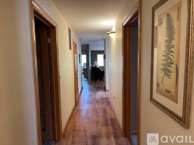 A hallway with wooden floors and a painting on the wall.