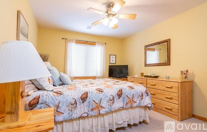 A bedroom with a bed, dresser, and ceiling fan.