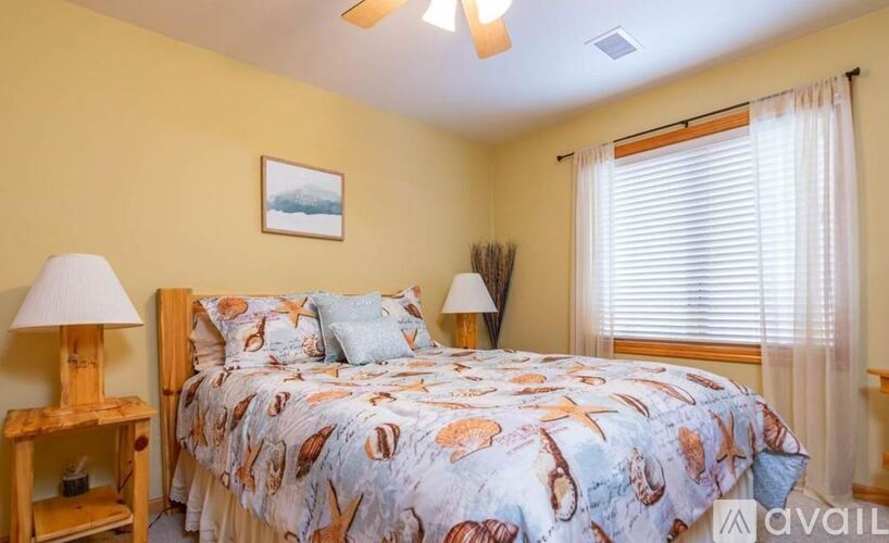 A bedroom with a bed, a lamp, and a picture on the wall.