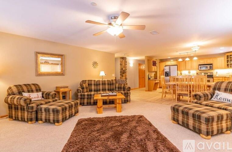 A living room with a brown rug and plaid furniture.
