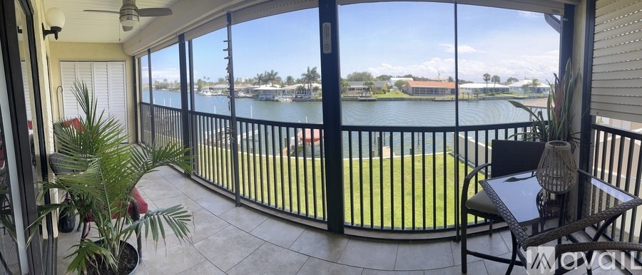 A balcony with a table and chairs overlooking a body of water.
