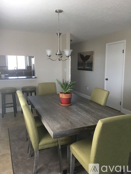 A dining room with a wooden table and green chairs.