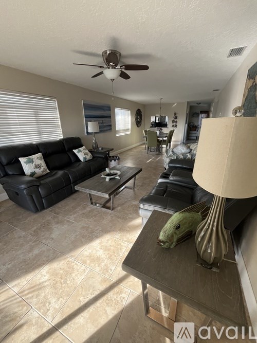 A living room with a black couch and a ceiling fan.