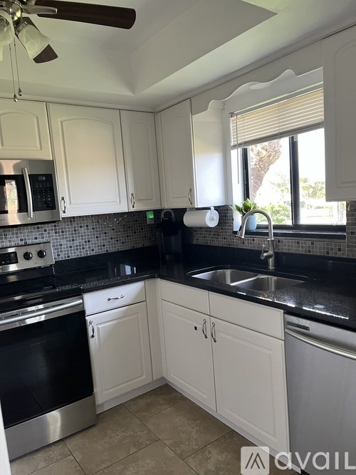 A kitchen with white cabinets and black countertops.