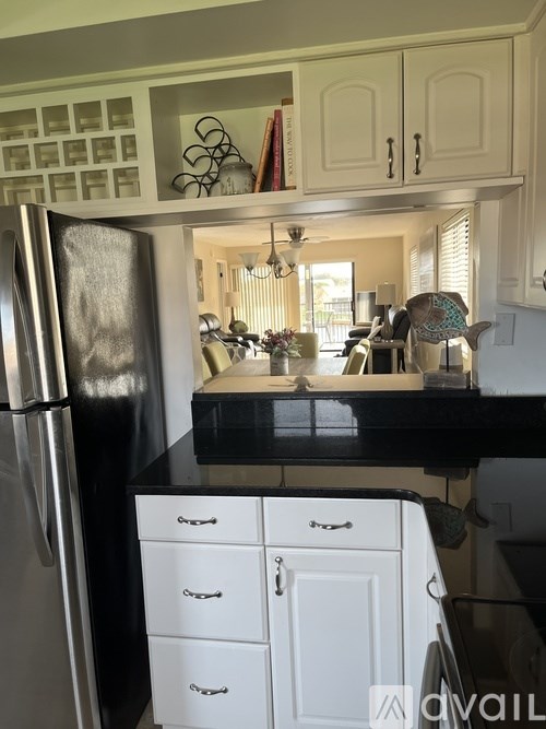 A kitchen with a black counter top and a stainless steel refrigerator.