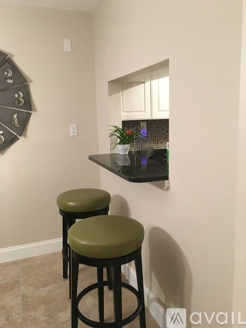 Two green bar stools are in front of a counter.
