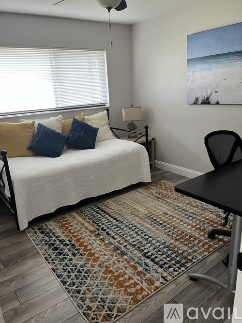 A bedroom with a bed, chair, and rug.