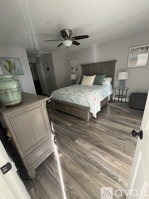 A bedroom with a bed, dresser, and ceiling fan.