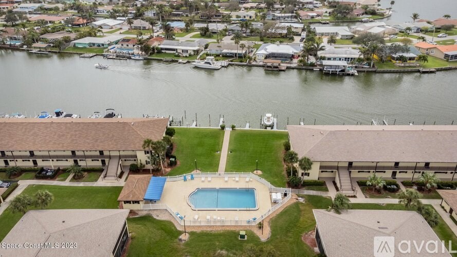 A bird's eye view of a house with a swimming pool in the foreground and a body of water in the background.