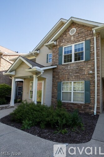 A house with a brown brick exterior and green shutters.