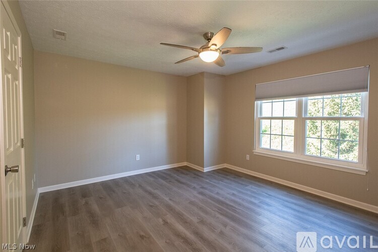 A spacious room with a ceiling fan and a window.