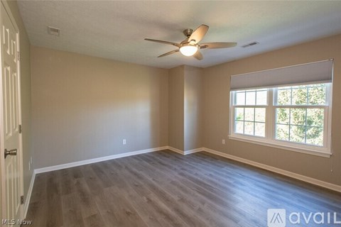A spacious room with a ceiling fan and a window.