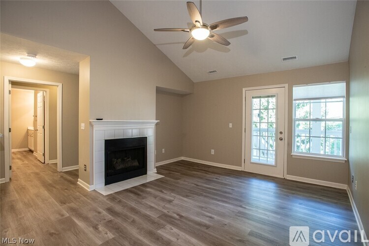 A spacious living room with a fireplace and a ceiling fan.