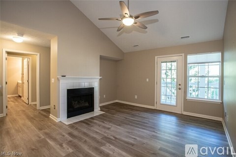 A spacious living room with a fireplace and a ceiling fan.