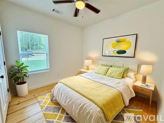 A bedroom with a bed, a ceiling fan, and a painting on the wall.