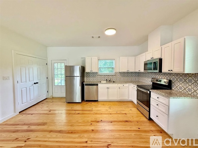 A kitchen with wooden floors and white cabinets.