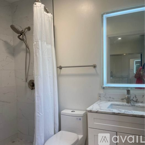 A white bathroom with a toilet, sink, and shower.