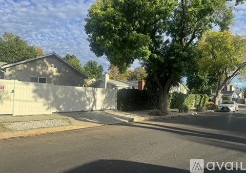 A street view with a house, trees, and a car parked on the side.